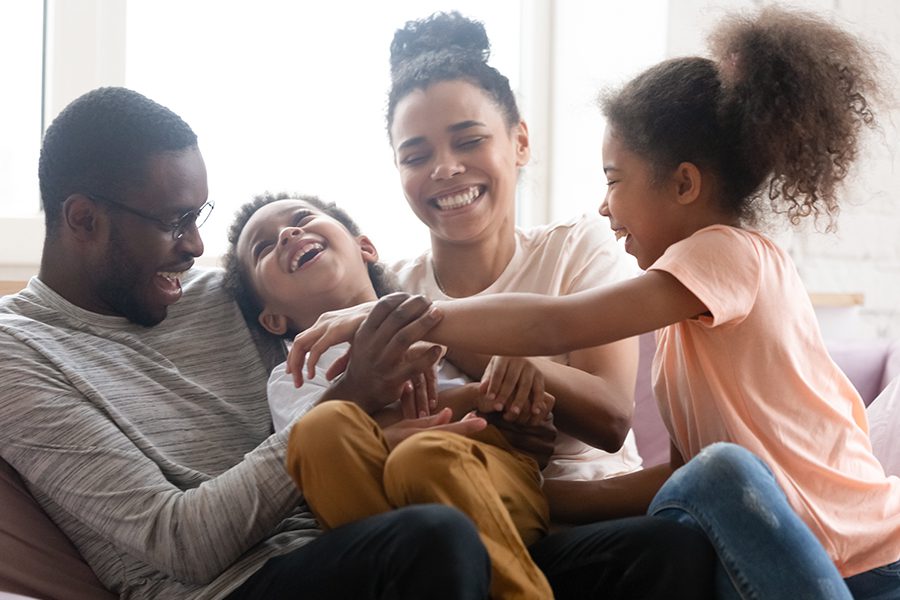 Personal Insurance - Family Sitting Together on the Living room Sofa, Having Fun and Laughing